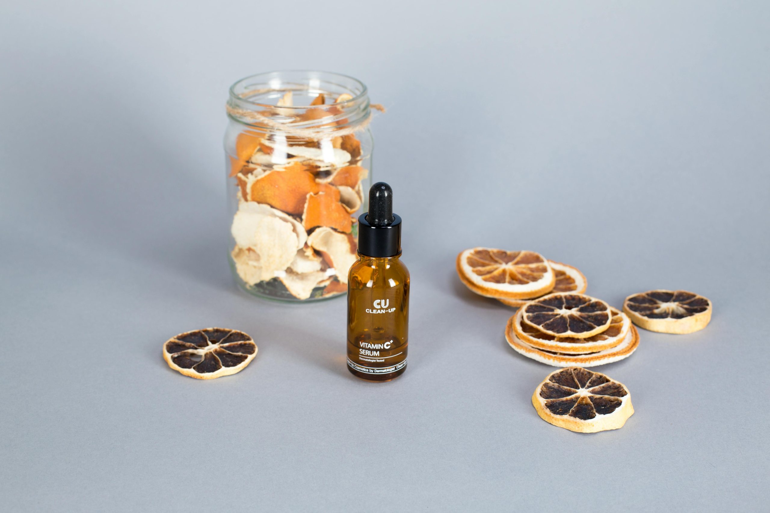 pexels photo 7817505 7817505 Product mockup of vitamin C serum with dried citrus slices and glass jar on a surface.